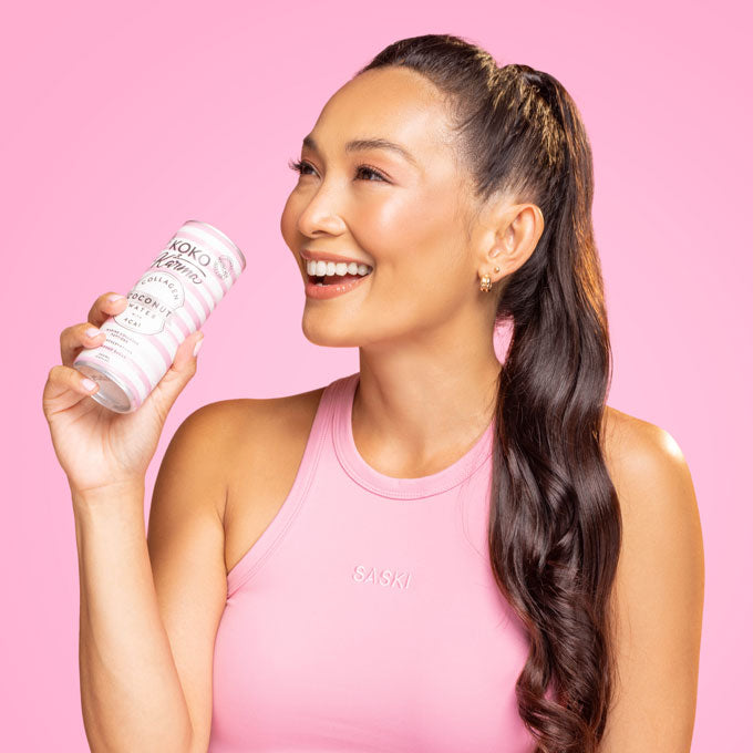 Holding a Koko and Karma Acai with Collagen Coconut Water