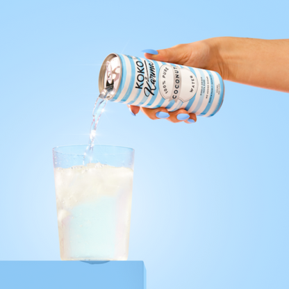 Pouring coconut water from Koko and Karma Pure Coconut can